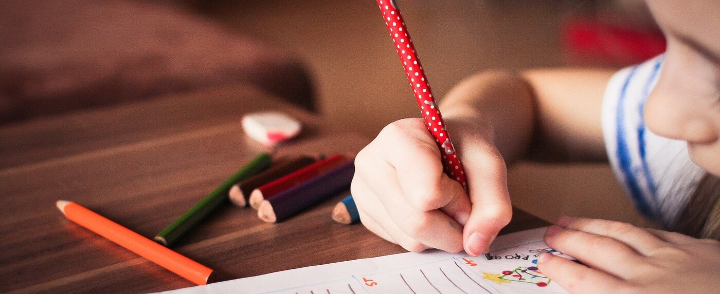 Kind hält Bleistift in der Hand.