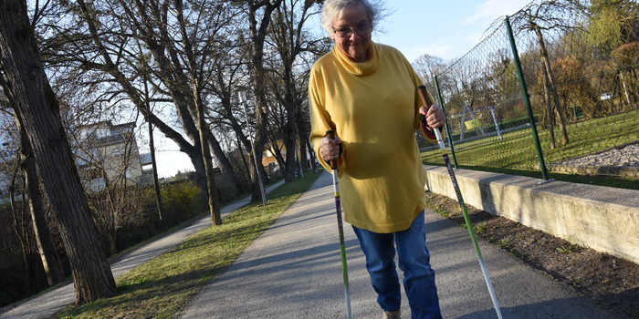 Ältere Dame spaziert auf einem Gehweg