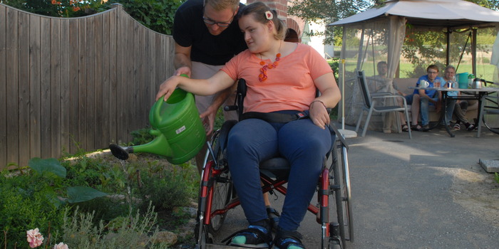 Frau im Rollstuhl gießt Blumen